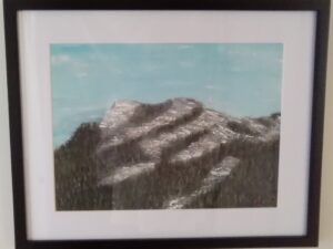 A painting of a mountain in a black frame.