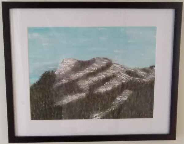 A painting of a mountain in a black frame.