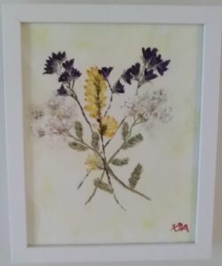 A framed painting of dried flowers in a white frame.