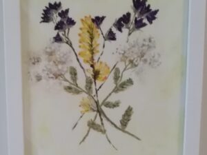 A framed painting of dried flowers in a white frame.