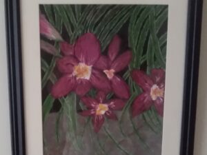 A framed painting of orchids in a black frame.