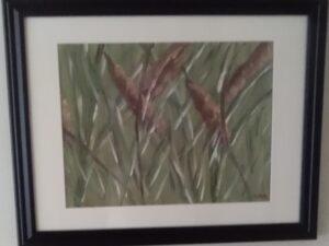 A painting of reeds in a black frame.