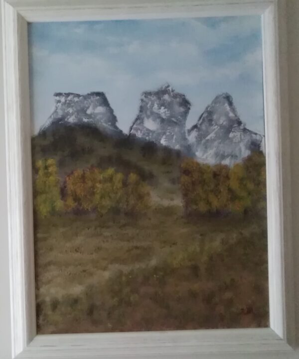 A painting of three mountains in a white frame.