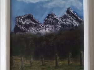 A painting of snowy mountains in a white frame.