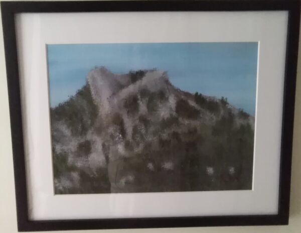 A framed painting of a mountain on a wall.