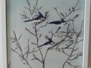 Three birds perched on a branch in a white frame.