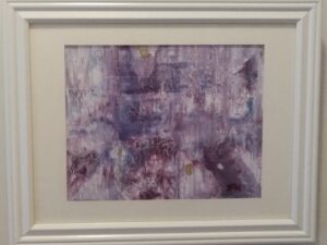 An abstract painting in a white frame on a wall.